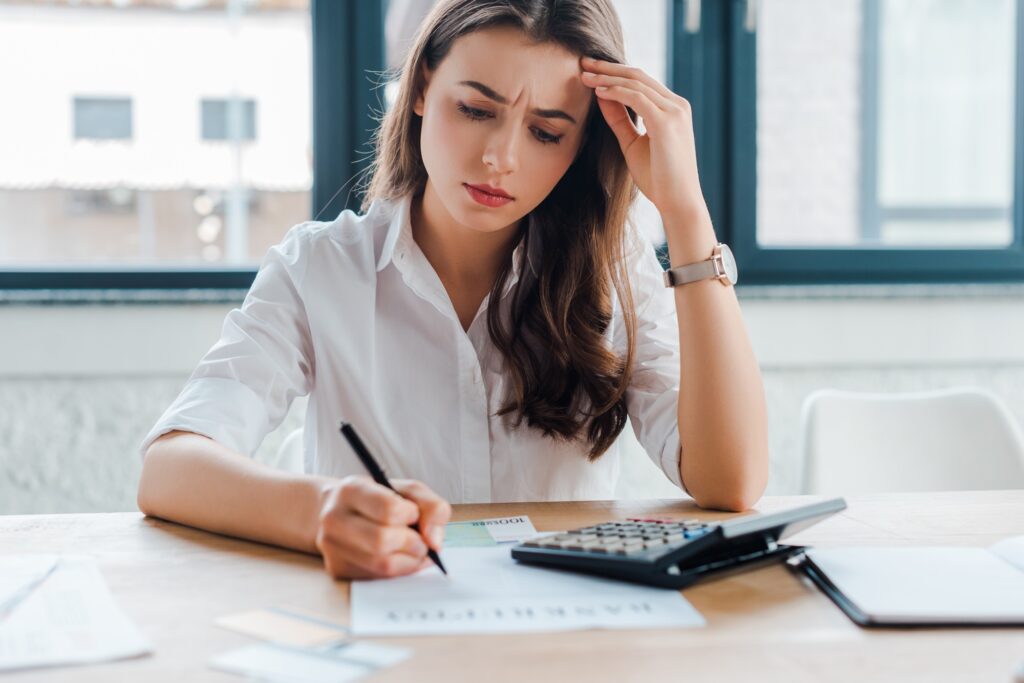 frustrated businesswoman signing document near calculator