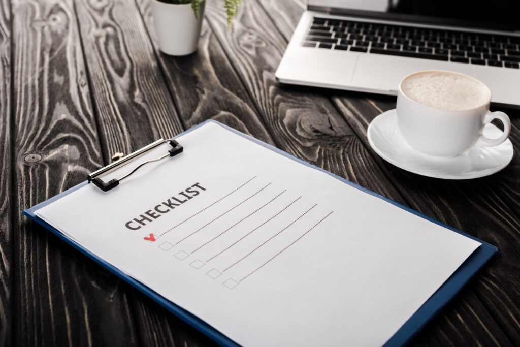 selective focus of clipboard with checklist near laptop and cup of coffee on table, e-commerce