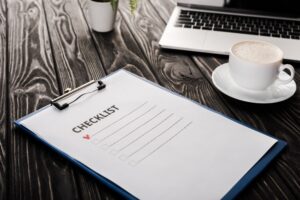 selective focus of clipboard with checklist near laptop and cup of coffee on table, e-commerce